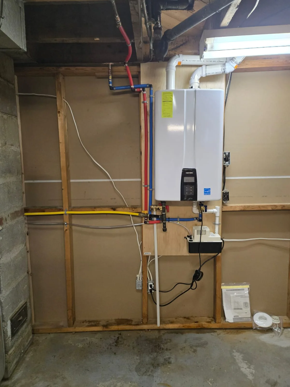 Completed Navien tankless water heater installation with condensate pump and water lines