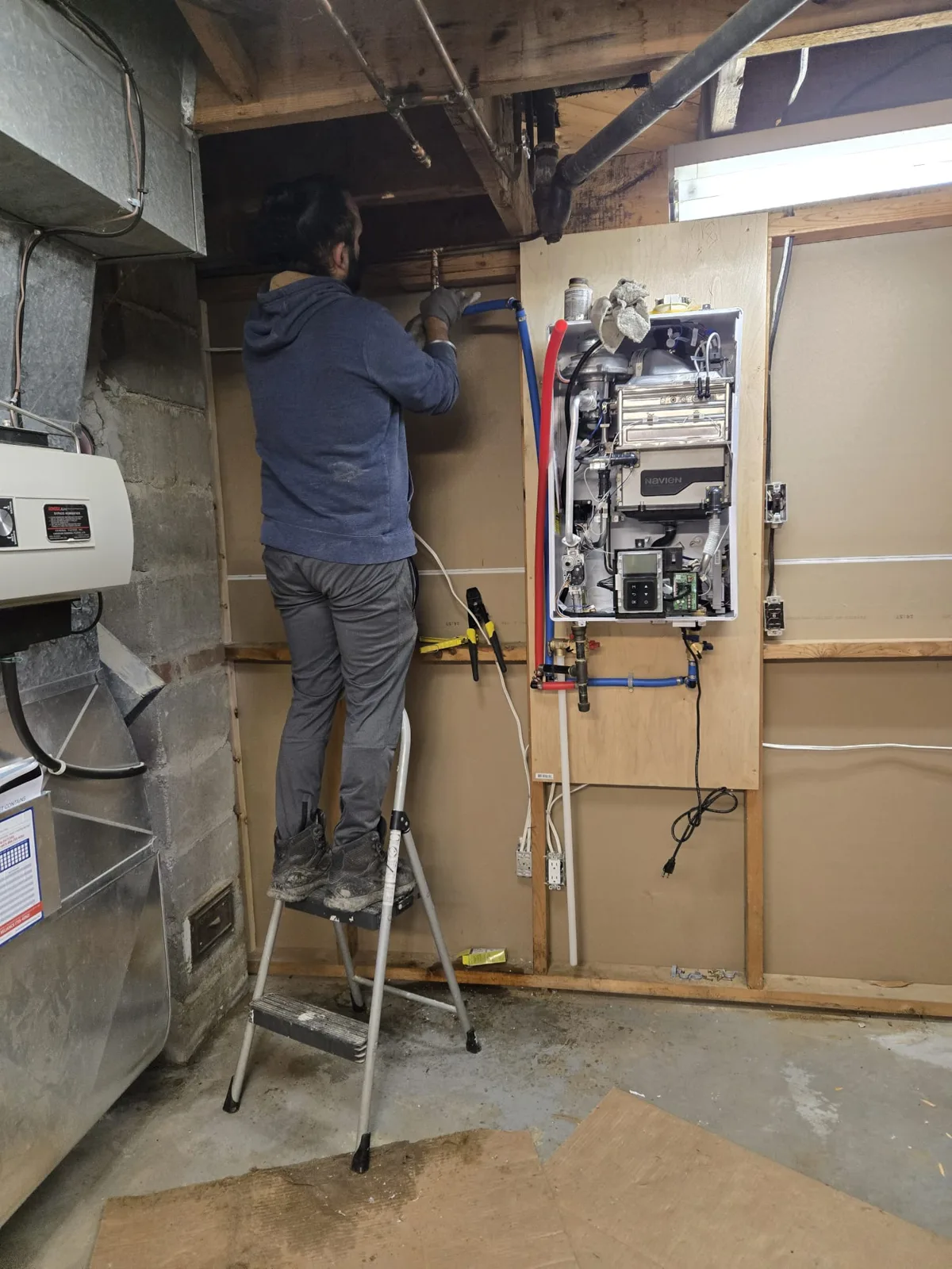 CITI HVAC technician running PEX water lines to a new Navien tankless water heater during a CV tank conversion