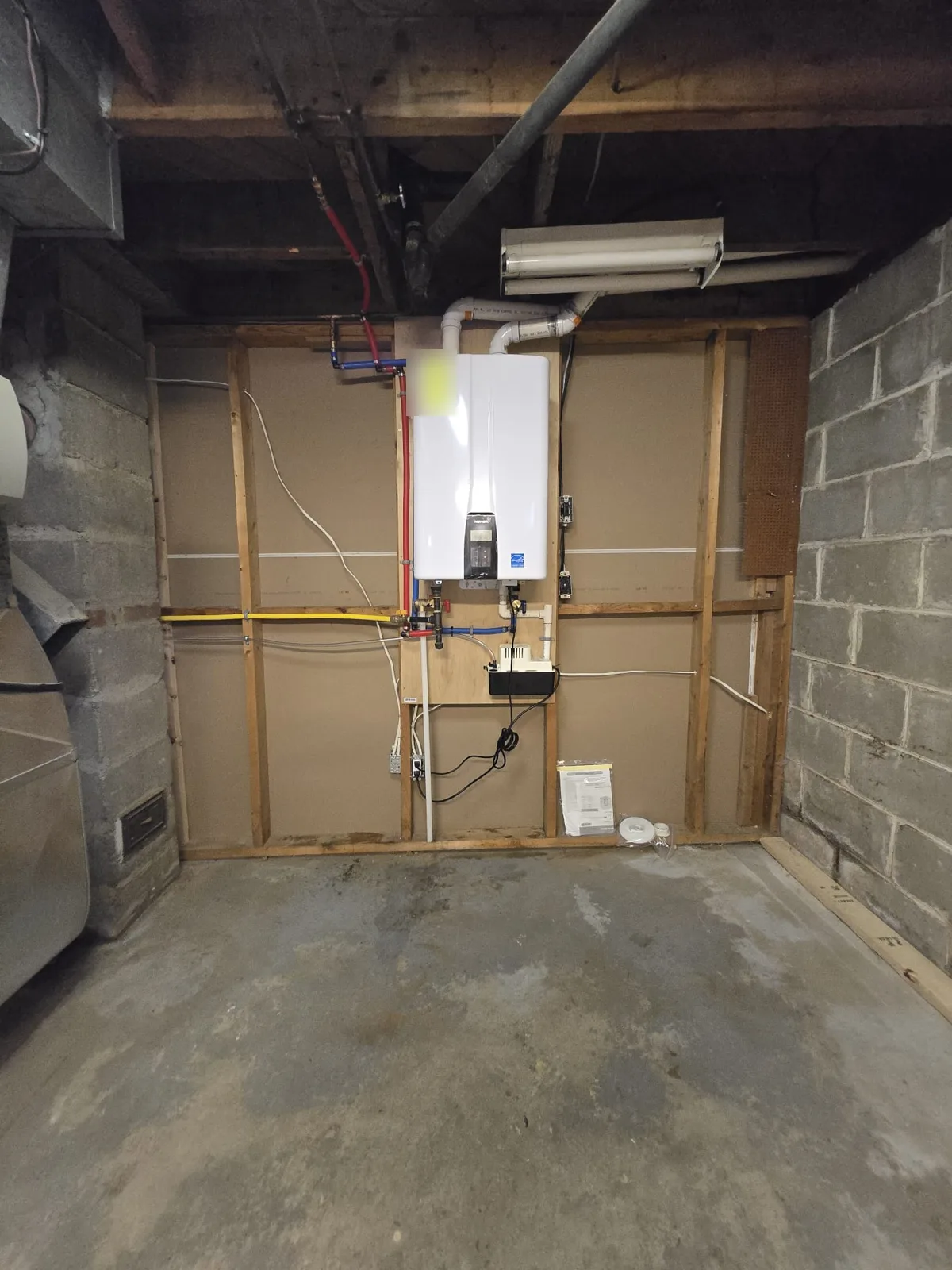 Finished Navien tankless water heater installation replacing a CV tank, with gas, PEX water lines and condensate pump