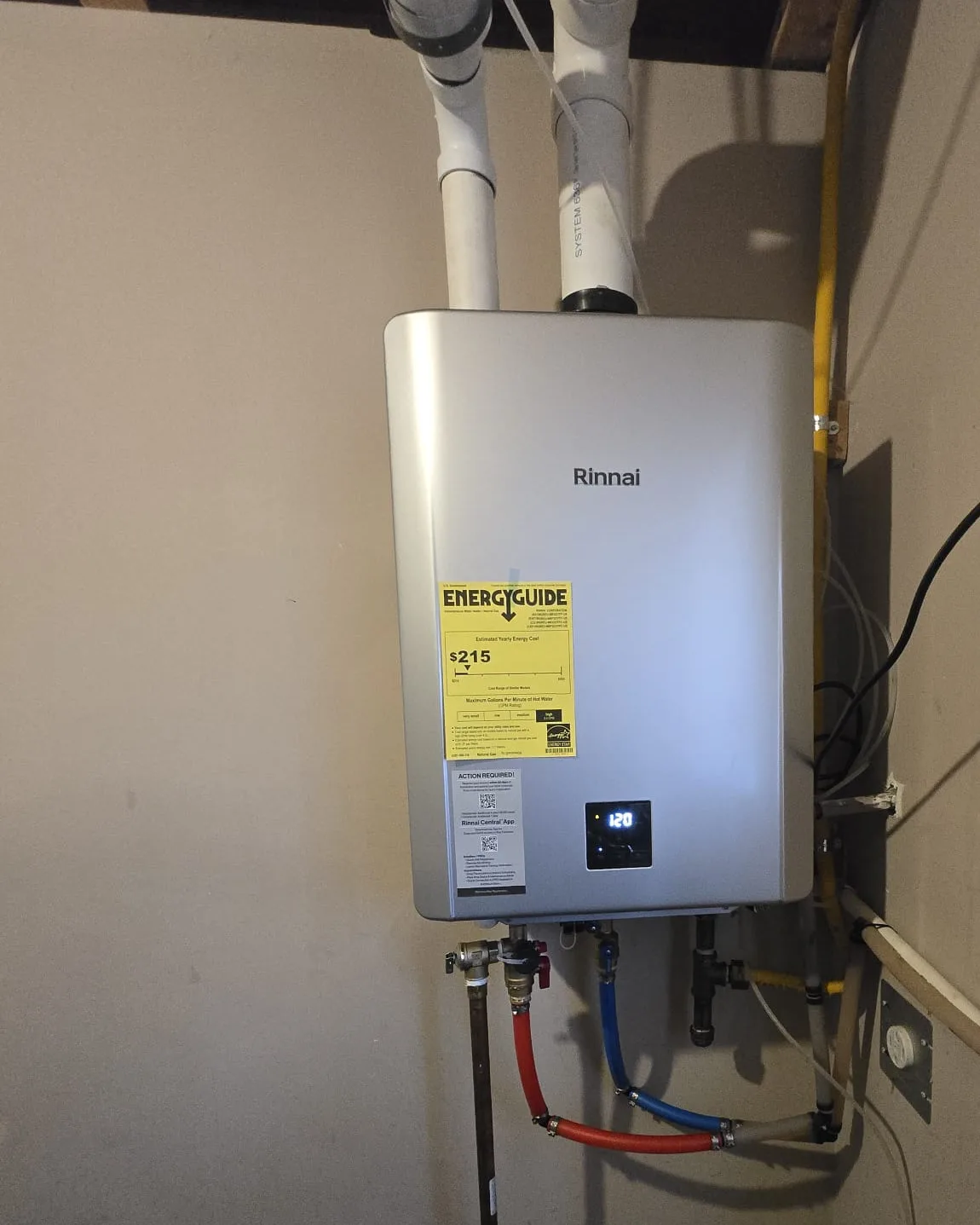 Rinnai tankless water heater close-up with PVC vent pipes, yellow gas line, PEX water lines and condensate line