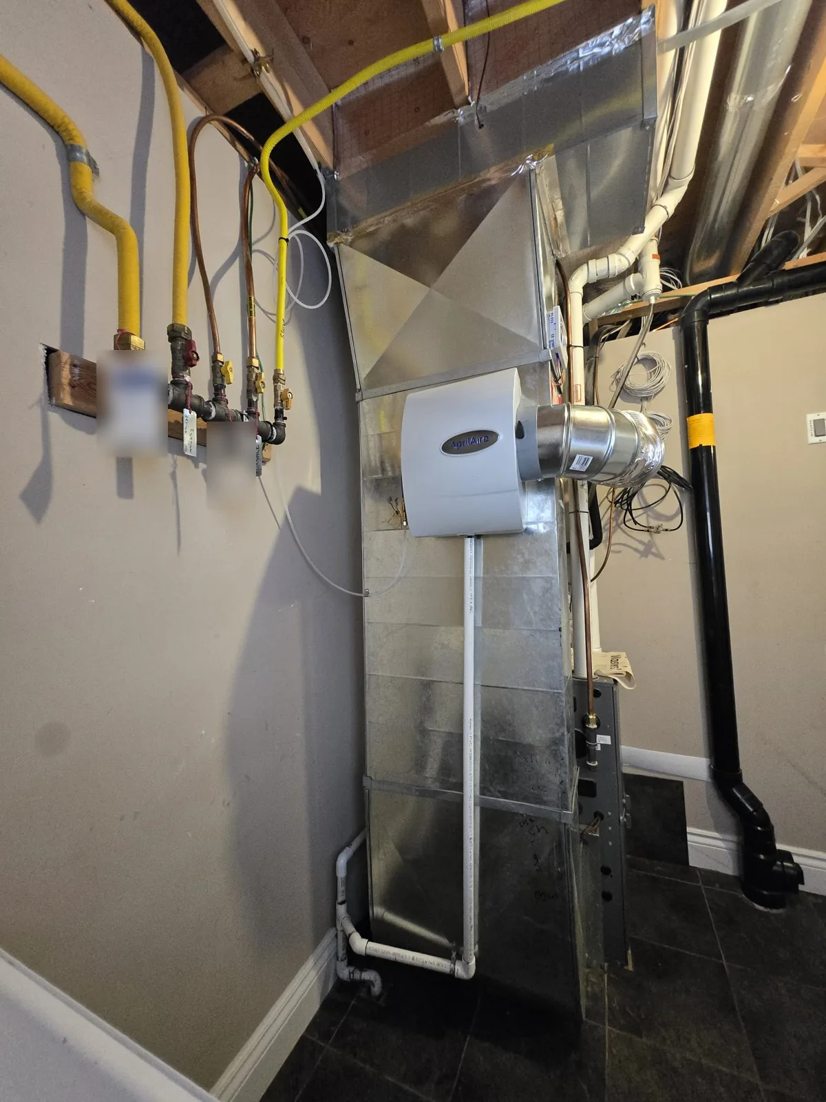 AprilAire whole-home humidifier installed on the furnace duct with water supply and drain